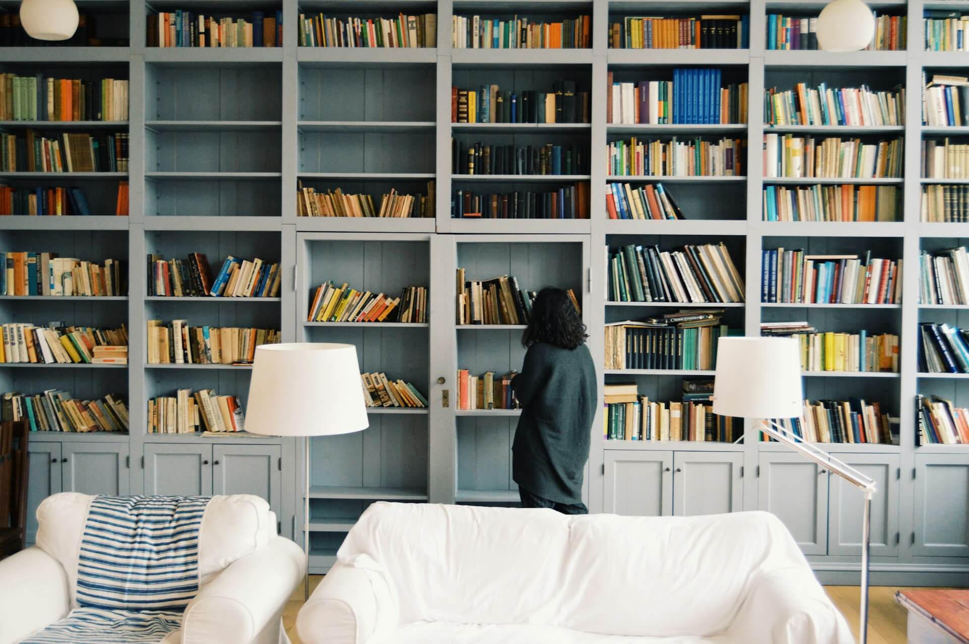 woman examining a floor to ceiling bookshelf